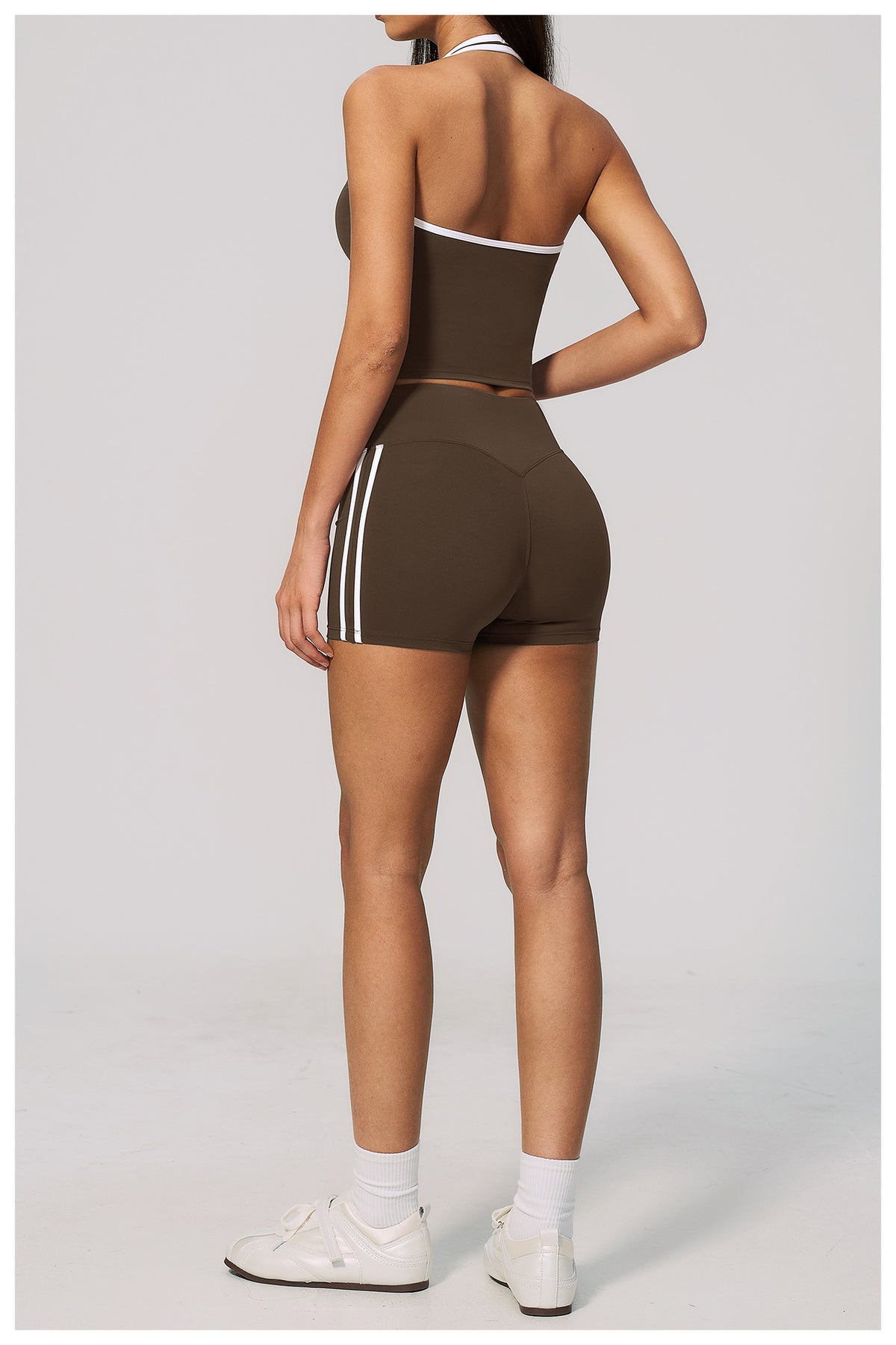 Person wearing a brown athletic outfit with white stripes on a light gray background