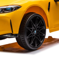 Yellow BMW M4 12V electric ride-on car for kids, featuring authentic design with working headlights, MP3 player, and forward/reverse motion. Comes with adjustable seat and steering wheel, providing a realistic driving experience for children aged 3-6