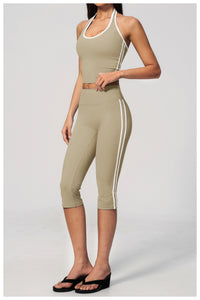 Woman wearing a beige athletic outfit with white stripes on a light gray background