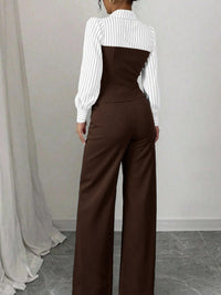 Person wearing a white blouse with a high collar and brown wide-leg pants against a plain background.