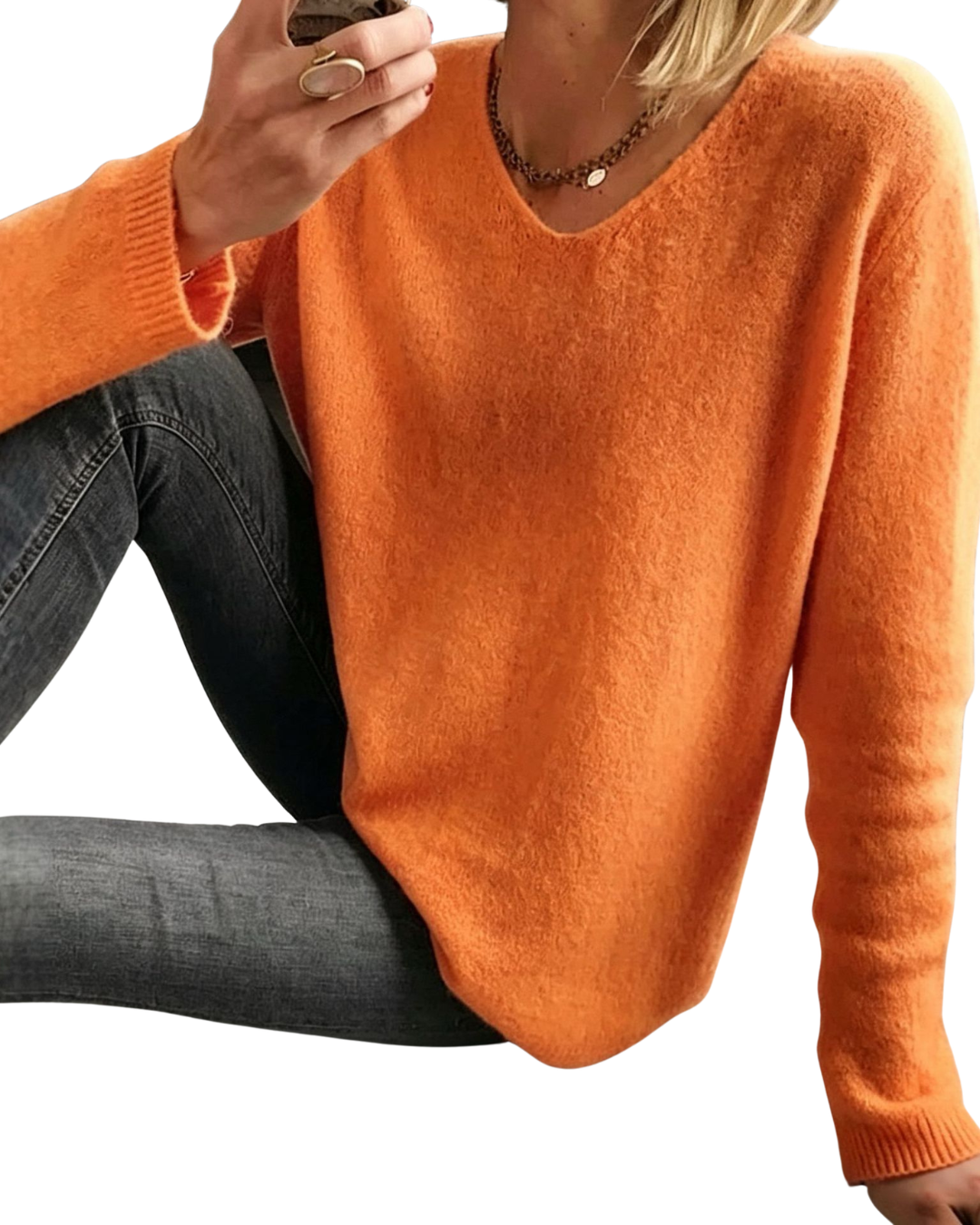 A woman wearing a fuzzy orange long-sleeve V-neck sweater and dark gray jeans, cropped from the mouth down against a plain white background.