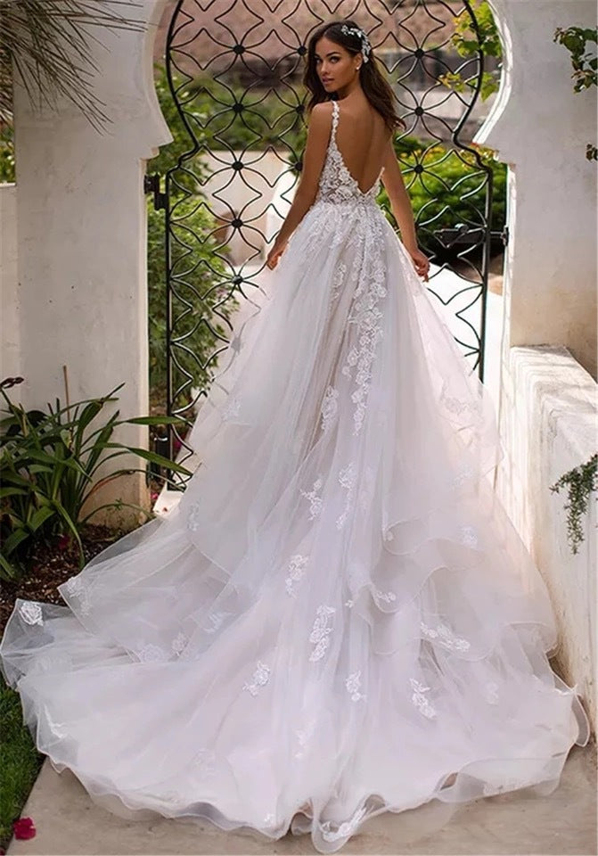 Elegant slim-fit wedding dress with a deep V-neckline, delicate suspender straps, and airy lightweight fabric, ideal for modern brides.

