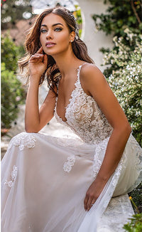 Elegant slim-fit wedding dress with a deep V-neckline, delicate suspender straps, and airy lightweight fabric, ideal for modern brides.

