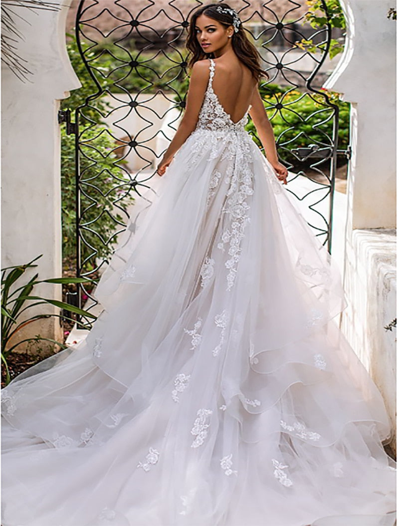 Elegant slim-fit wedding dress with a deep V-neckline, delicate suspender straps, and airy lightweight fabric, ideal for modern brides.

