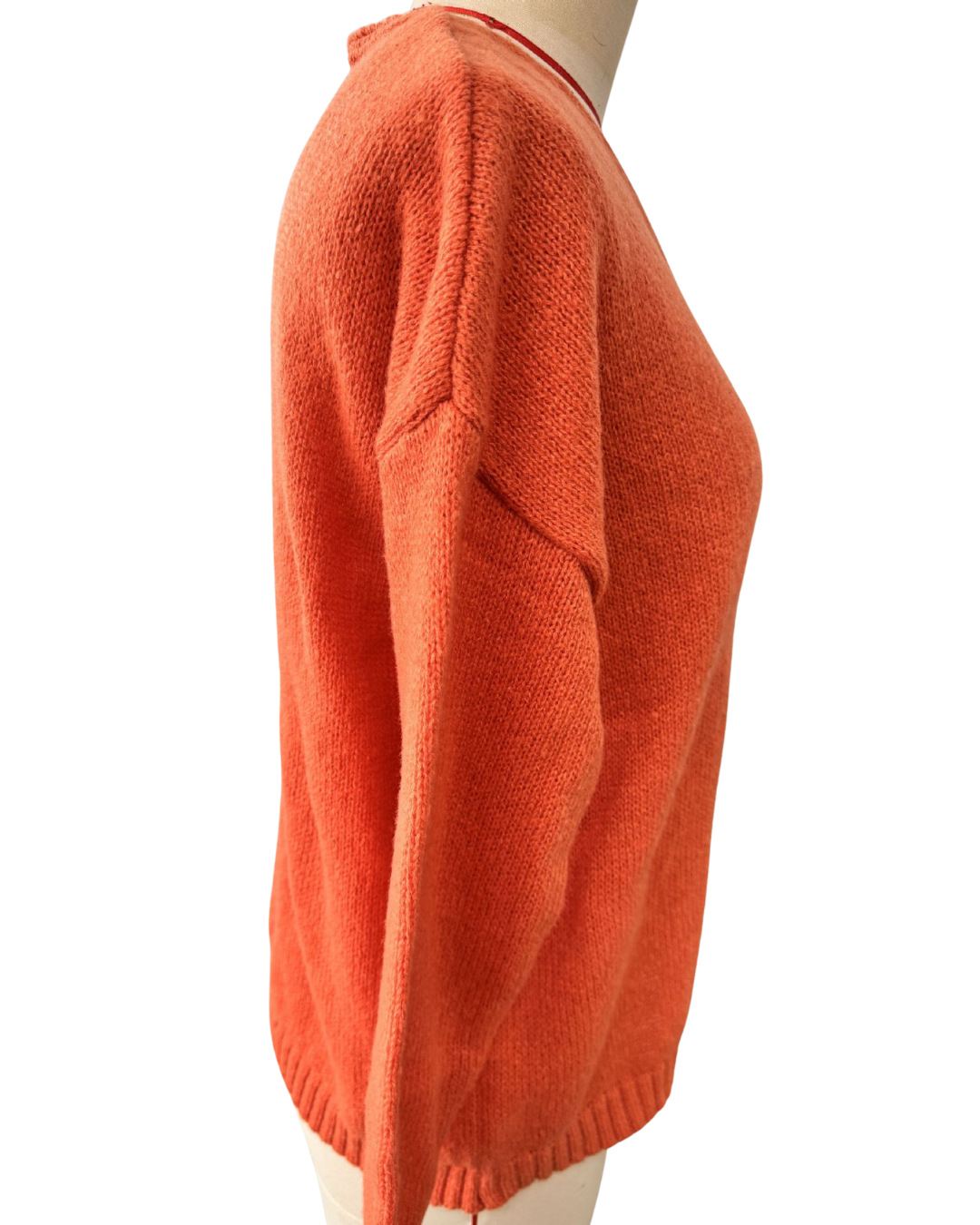 An orange knit sweater shown from the side on a mannequin against a plain white background.