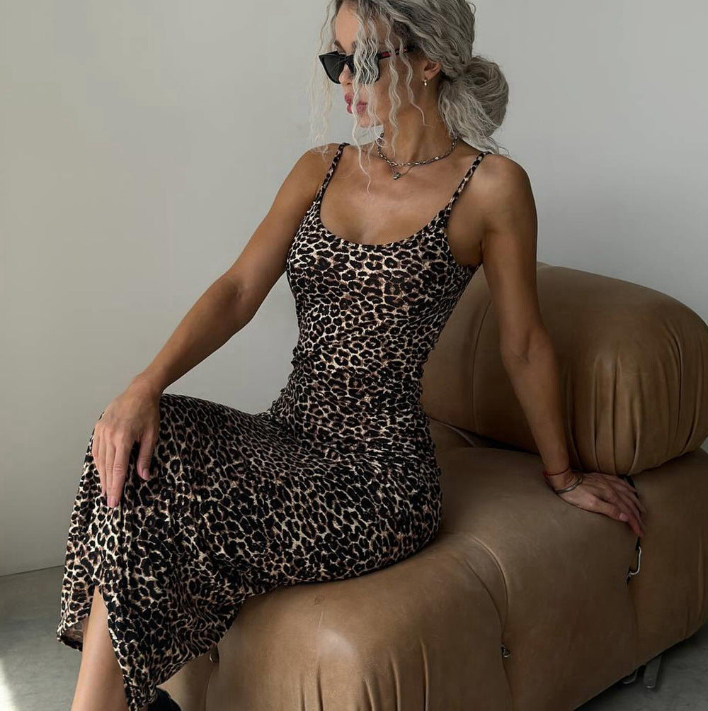 Woman in a leopard print dress sitting on a brown couch against a plain wall.