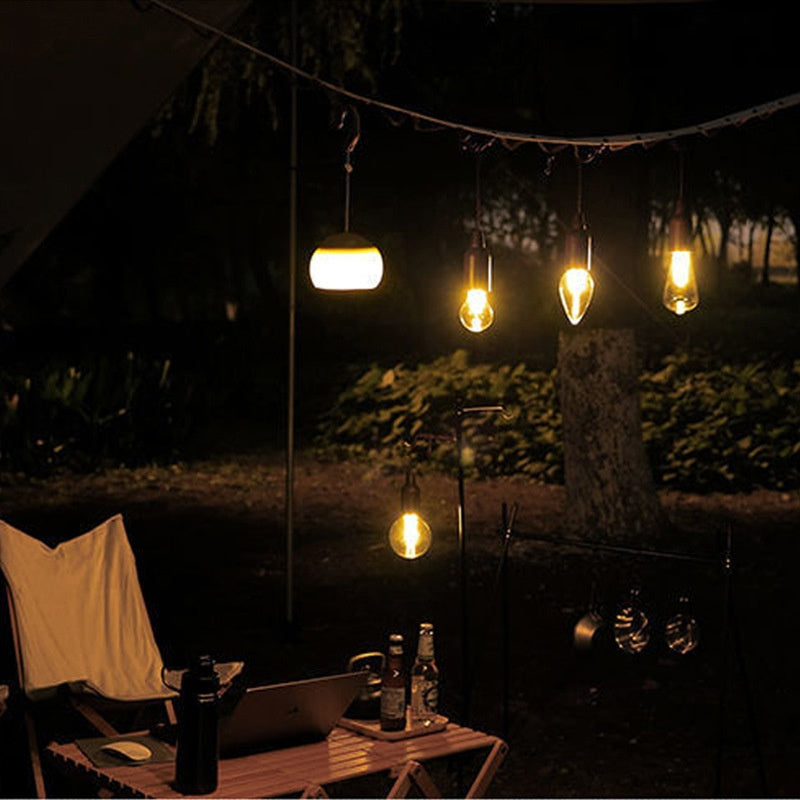 Solar-powered camping lantern with tungsten bulb hanging in a tent outdoors


