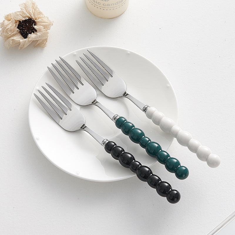 Set of 4 high-end stainless steel cutlery with colorful pearl handles on an elegant dining table