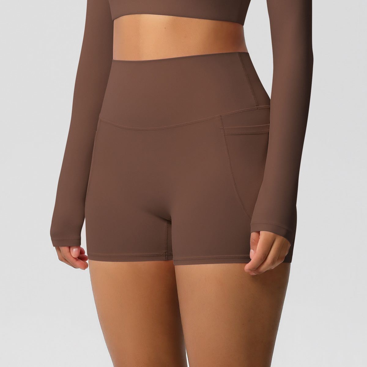 Brown athletic outfit with long-sleeve top and shorts on a plain background