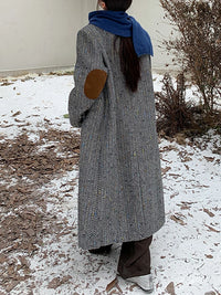 Model wearing a solid plaid minimalist woolen coat in a city street setting