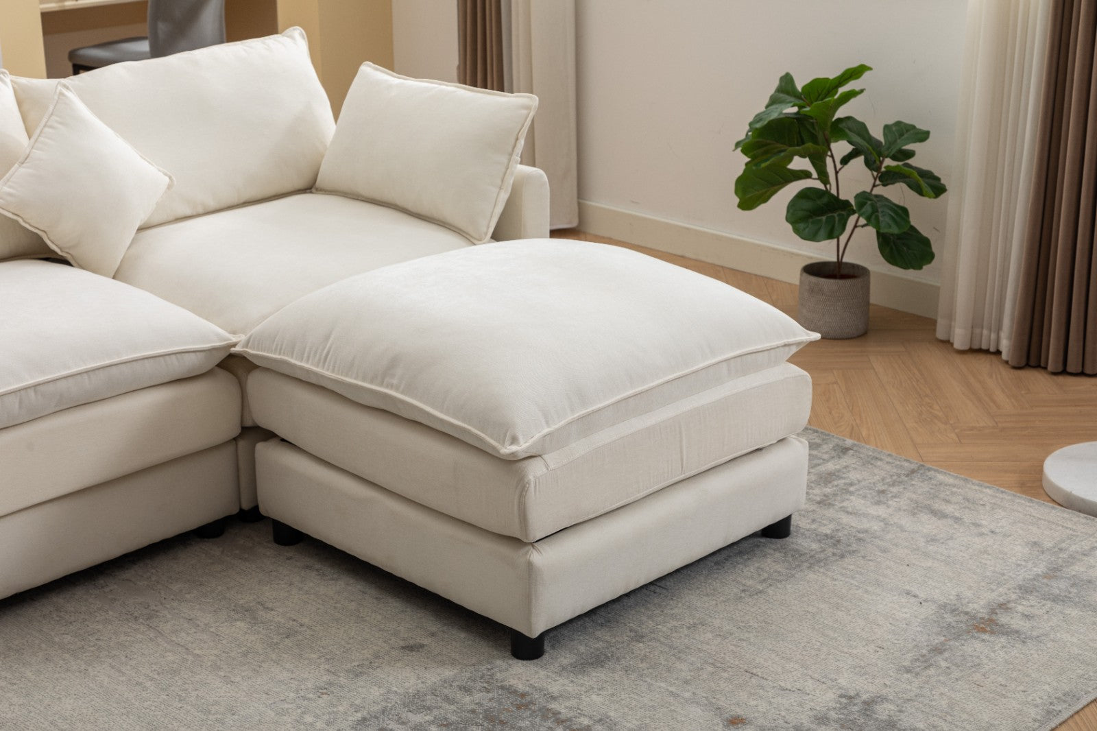 Modern L-shaped 3-seater modular sofa with ottoman in a living room setting.

