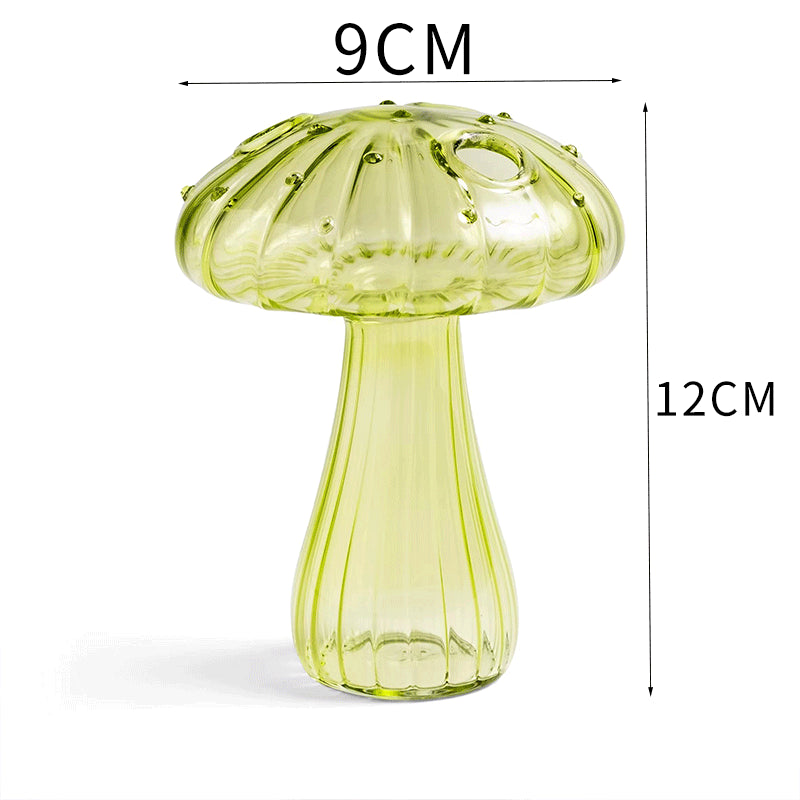 Clear glass mushroom-shaped vase with hydroponic plant and flowers on a minimalist home table

