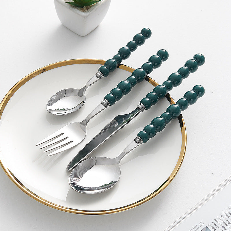 Set of 4 high-end stainless steel cutlery with colorful pearl handles on an elegant dining table
