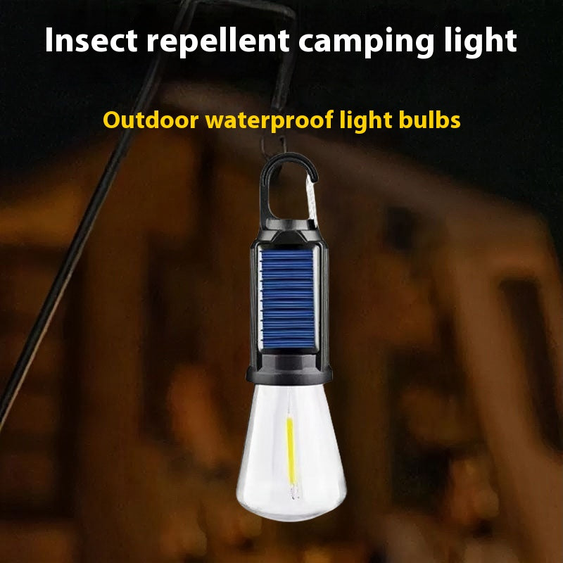 Solar-powered camping lantern with tungsten bulb hanging in a tent outdoors

