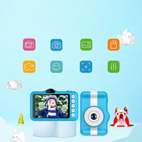 A children's instant camera shown in a stylized graphic layout. The product consists of a light blue body with a white vertical stripe, a circular lens, and a small side button.