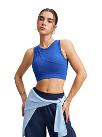 A woman modeling a royal blue ribbed athletic crop top and navy blue athletic pants with a light blue shirt tied around the waist, set against a solid white background.