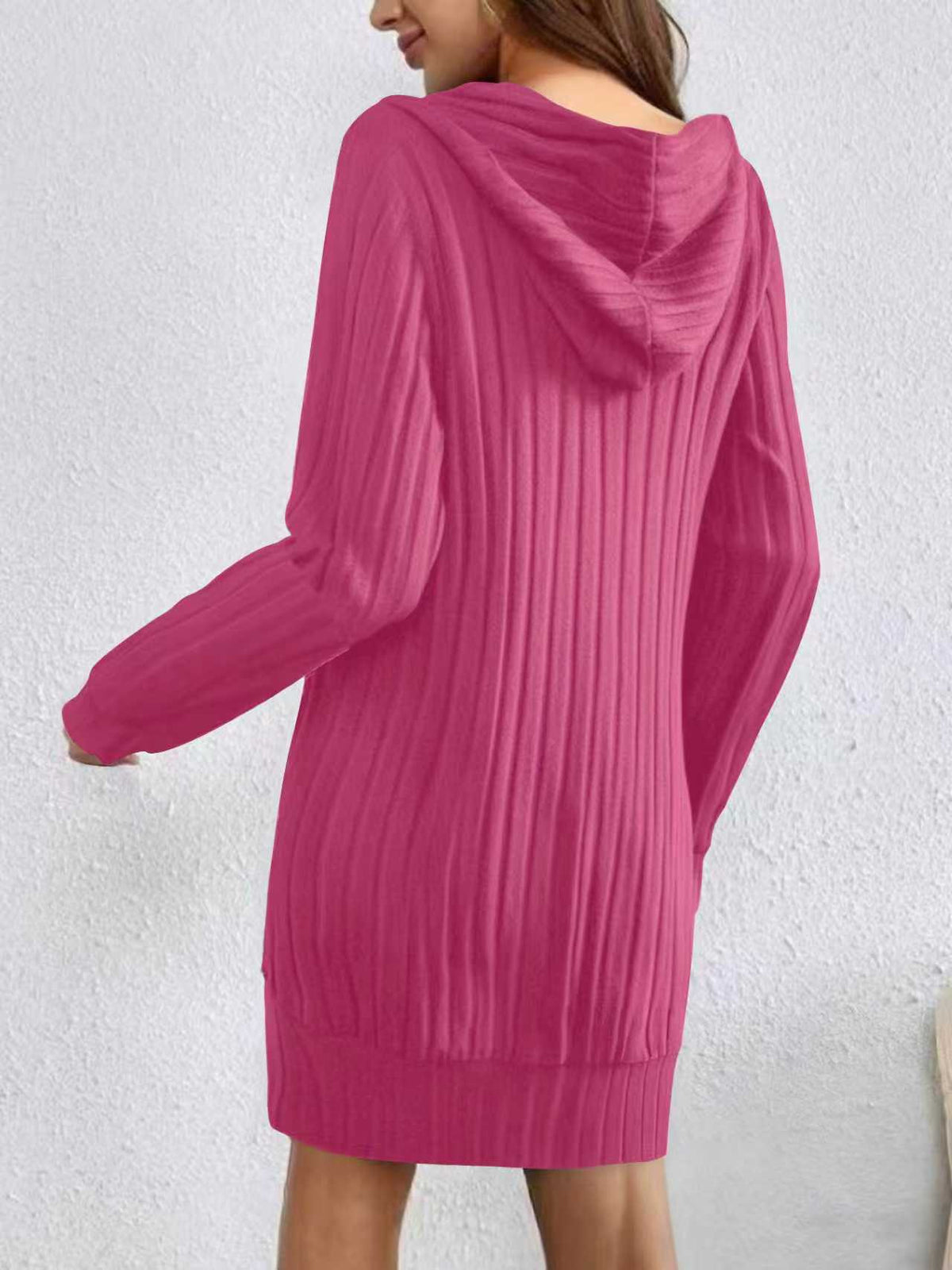 Pink hooded sweater dress worn by a person on a white background