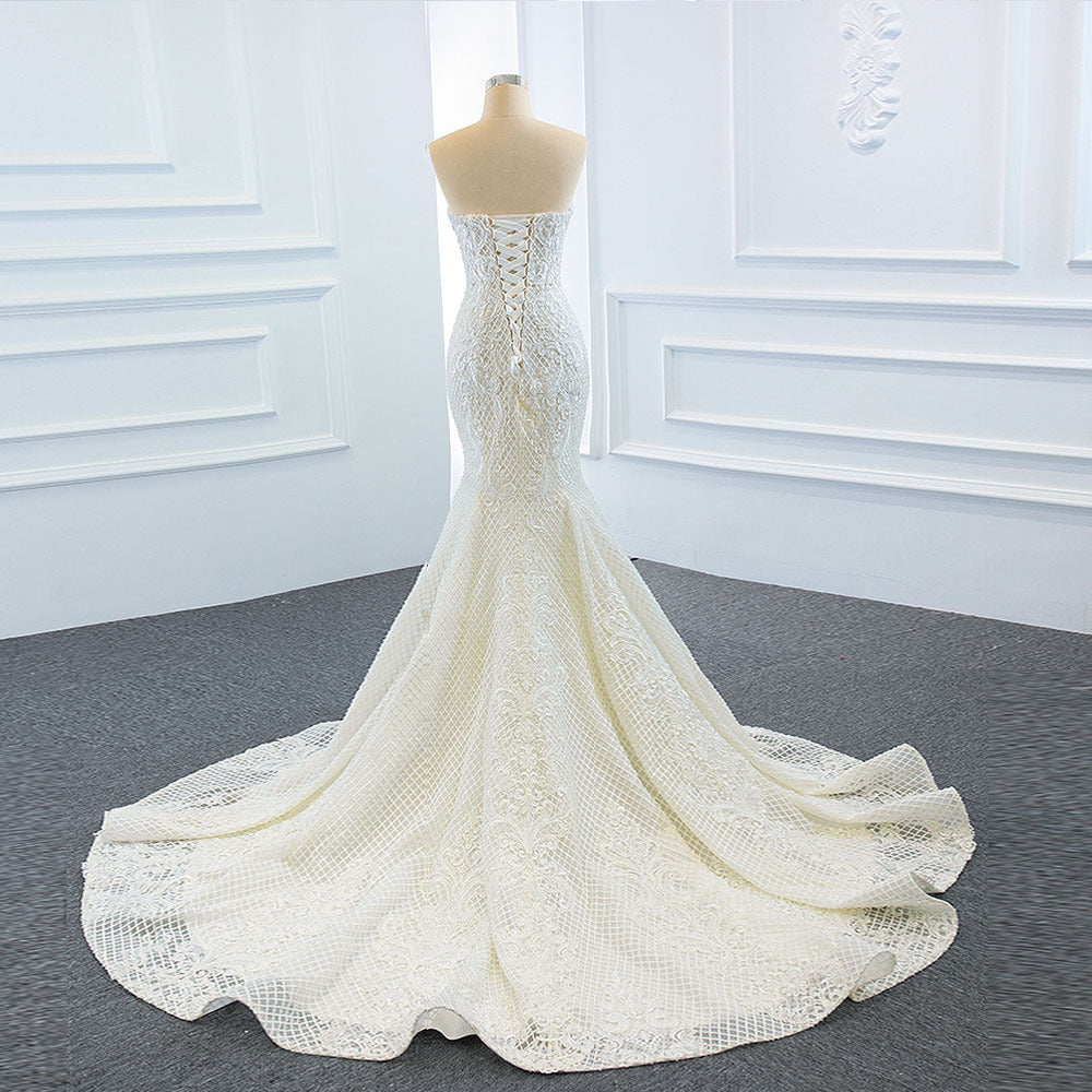Elegant strapless tube top wedding dress with a fishtail silhouette, detachable flowing train, and intricate lace details for a dreamy bridal look.

