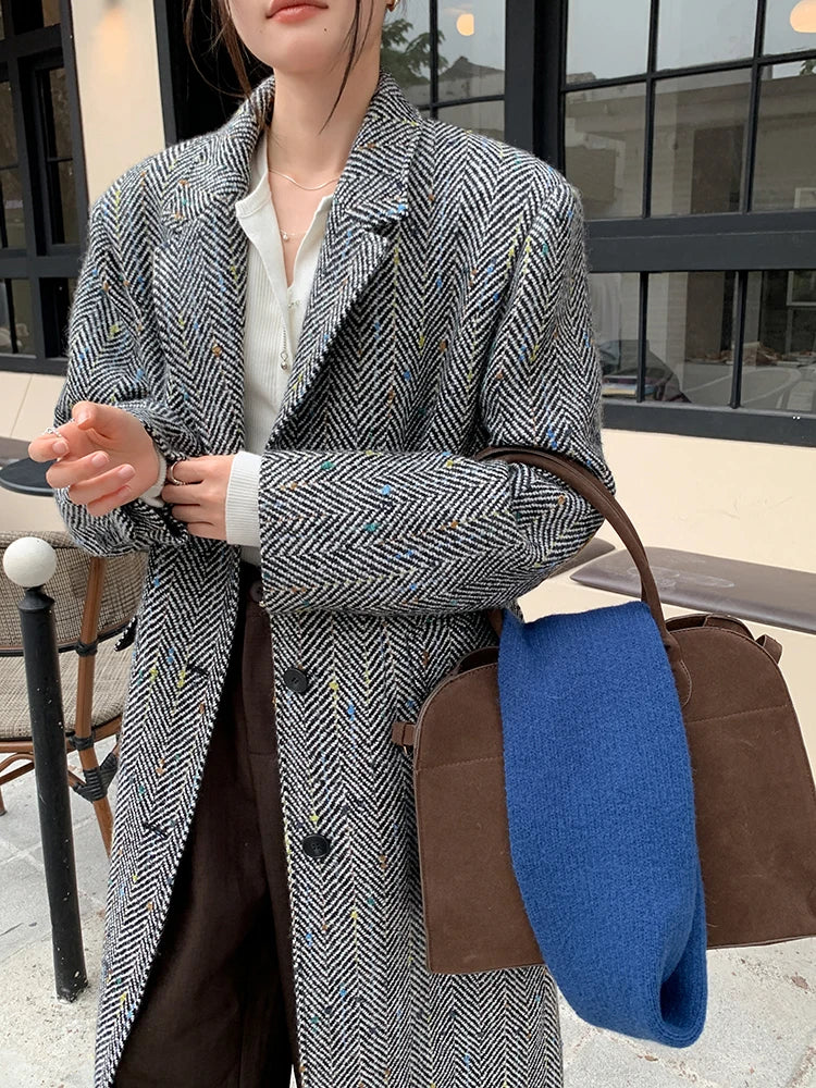 Model wearing a solid plaid minimalist woolen coat in a city street setting