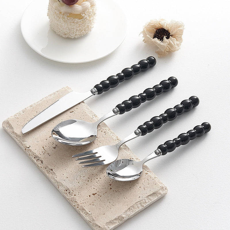 Set of 4 high-end stainless steel cutlery with colorful pearl handles on an elegant dining table
