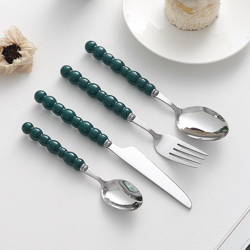 Set of 4 high-end stainless steel cutlery with colorful pearl handles on an elegant dining table