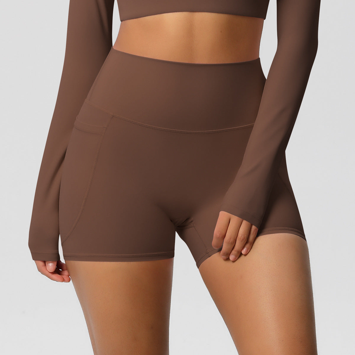 Brown athletic outfit with long sleeves and shorts on a plain background