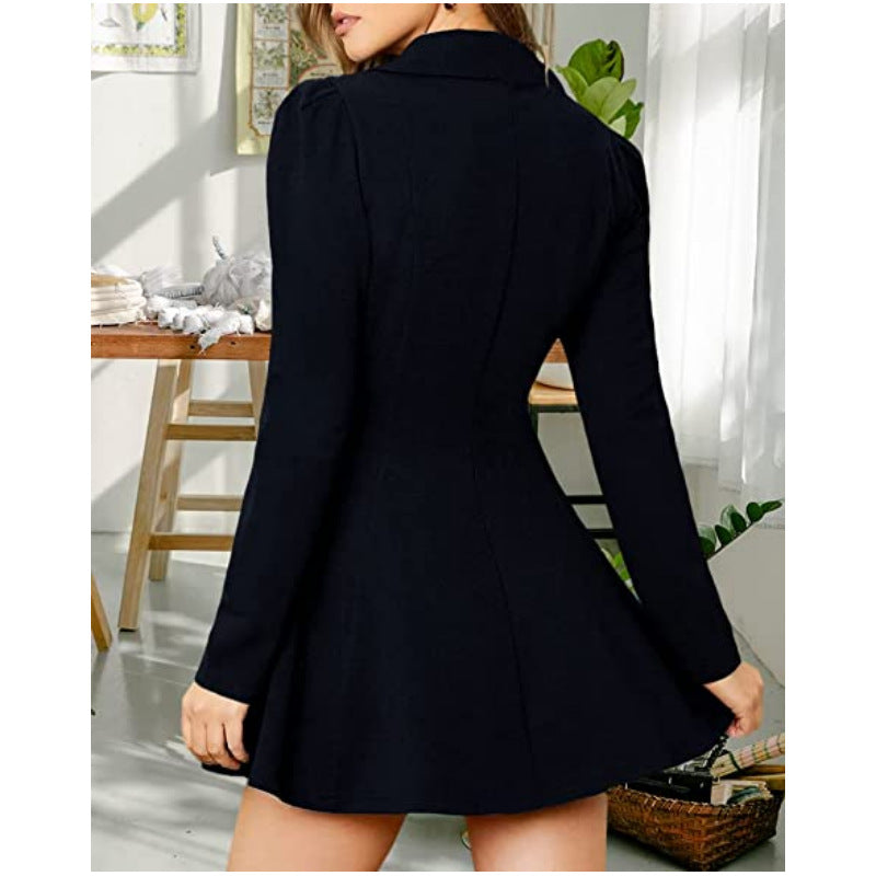A woman wearing a black long-sleeve mini dress with a high collar and flared skirt, shown from the back in a bright indoor room.