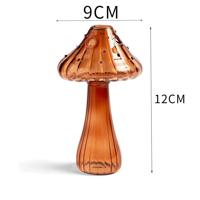 Clear glass mushroom-shaped vase with hydroponic plant and flowers on a minimalist home table

