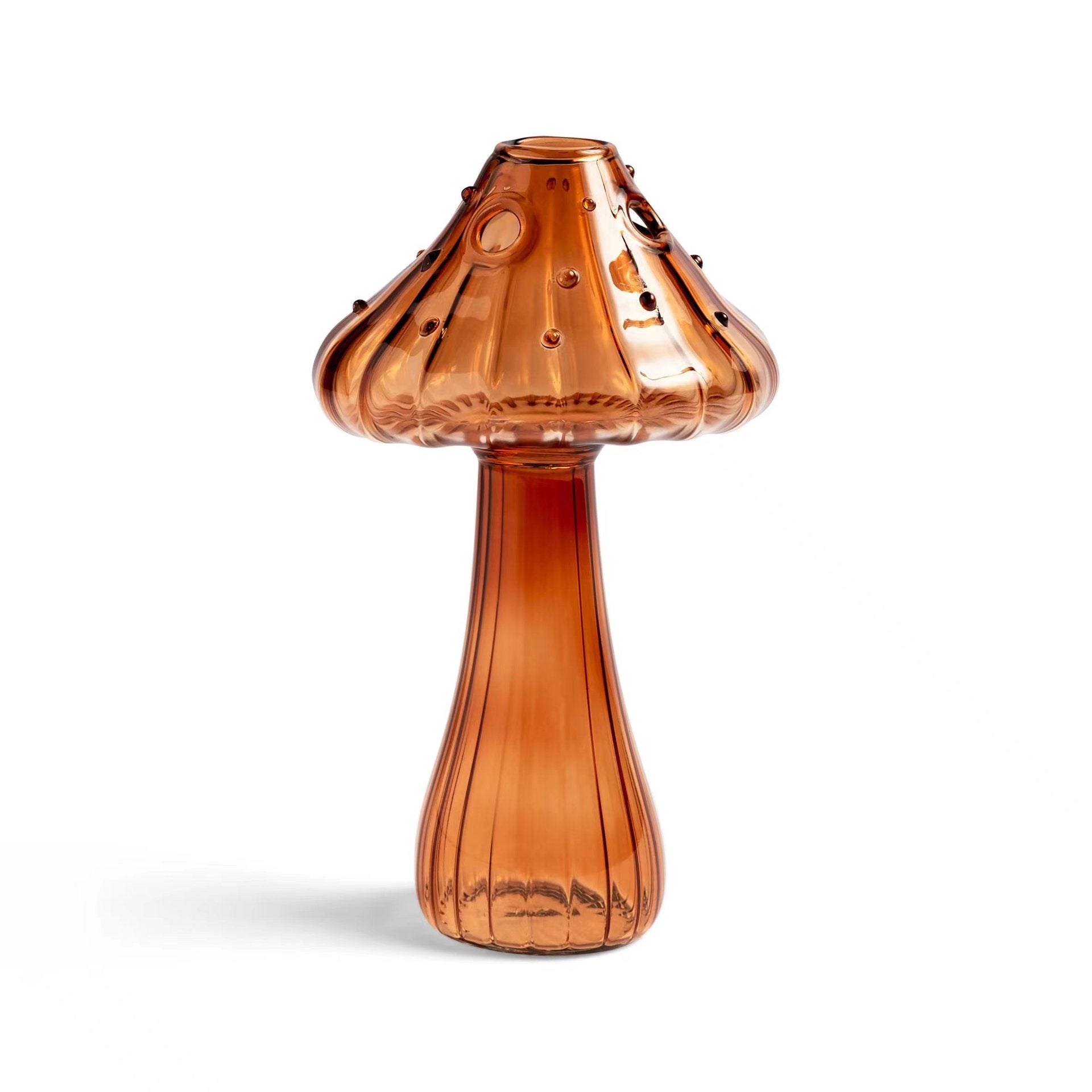 Clear glass mushroom-shaped vase with hydroponic plant and flowers on a minimalist home table

