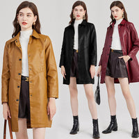 Model wearing a long black PU leather jacket styled with winter boots and a scarf