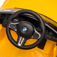 Yellow BMW M4 12V electric ride-on car for kids, featuring authentic design with working headlights, MP3 player, and forward/reverse motion. Comes with adjustable seat and steering wheel, providing a realistic driving experience for children aged 3-6