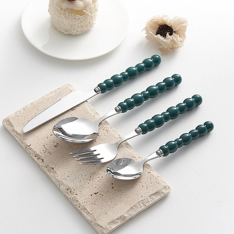 Set of 4 high-end stainless steel cutlery with colorful pearl handles on an elegant dining table
