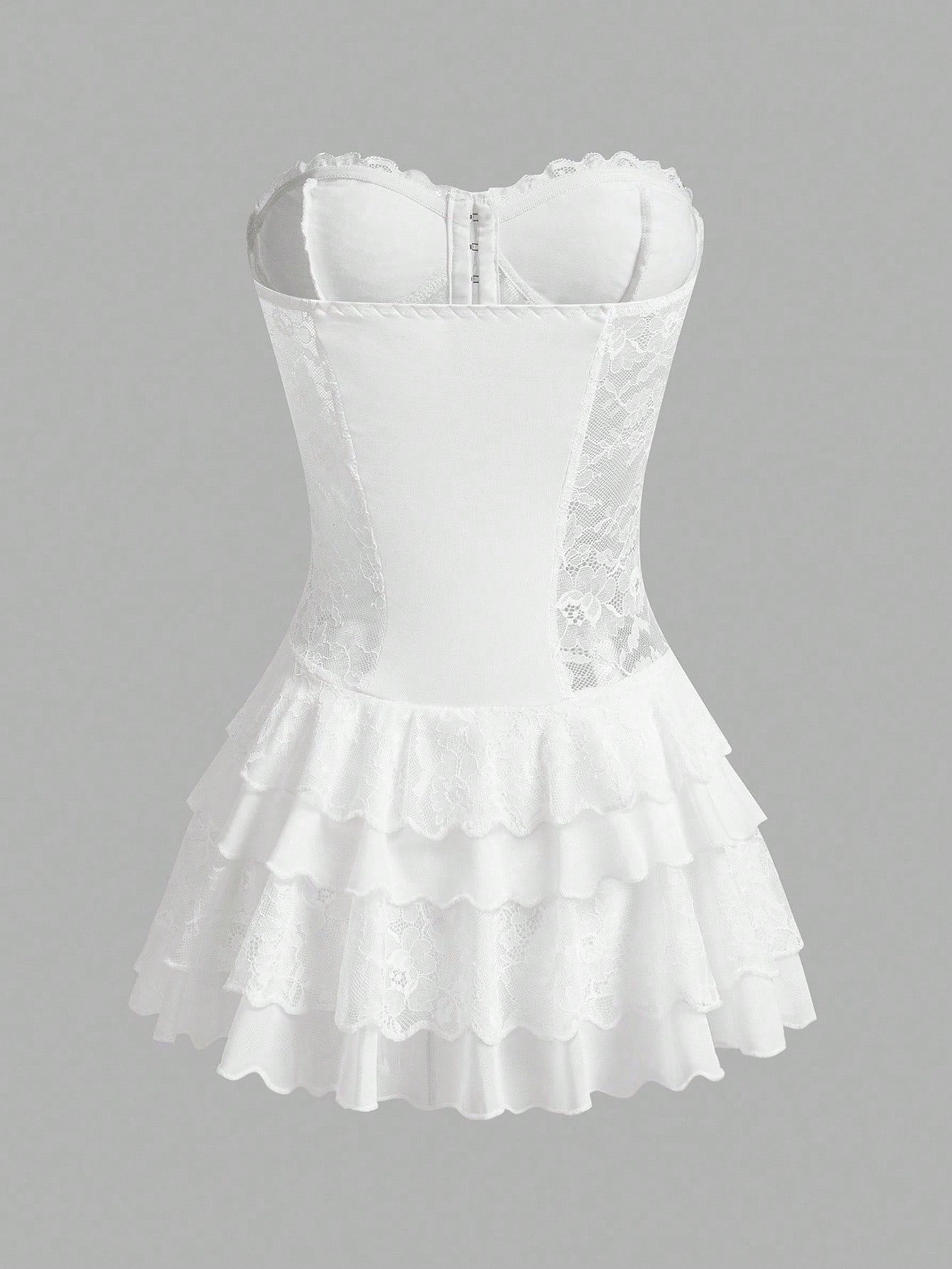 White corset-style mini dress with lace trim, structured bust, and tiered ruffled skirt on a plain gray background.