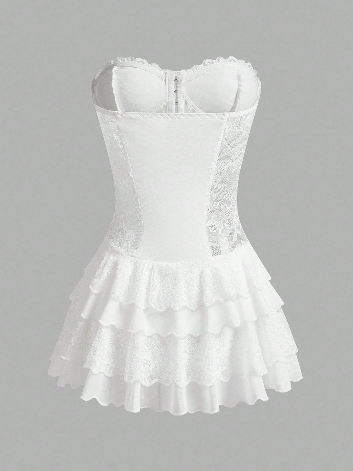 White corset-style mini dress with lace trim, structured bust, and tiered ruffled skirt on a plain gray background.