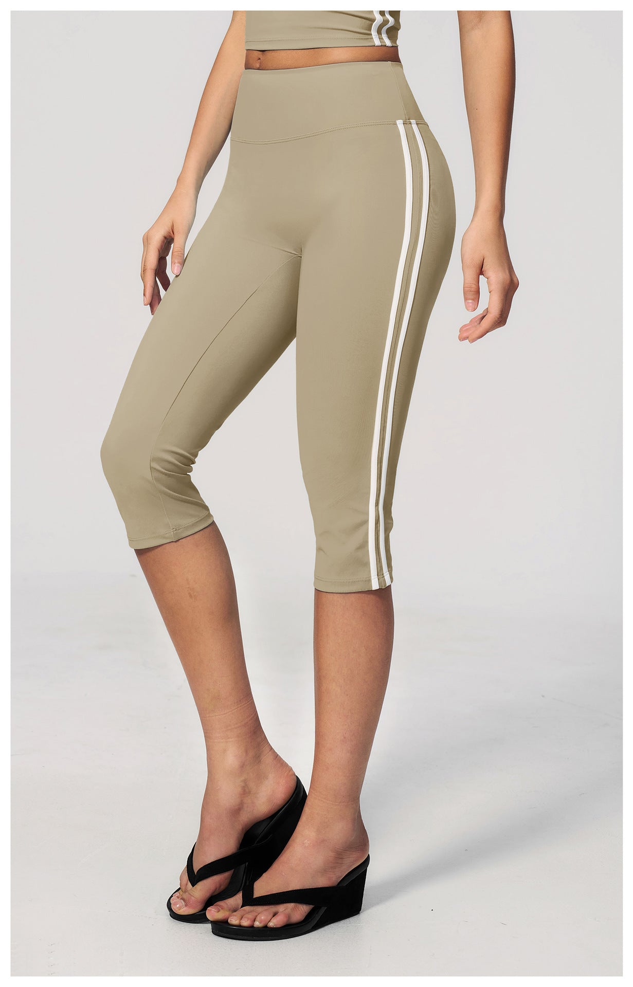 Beige capri leggings with white stripes worn by a person on a light gray background