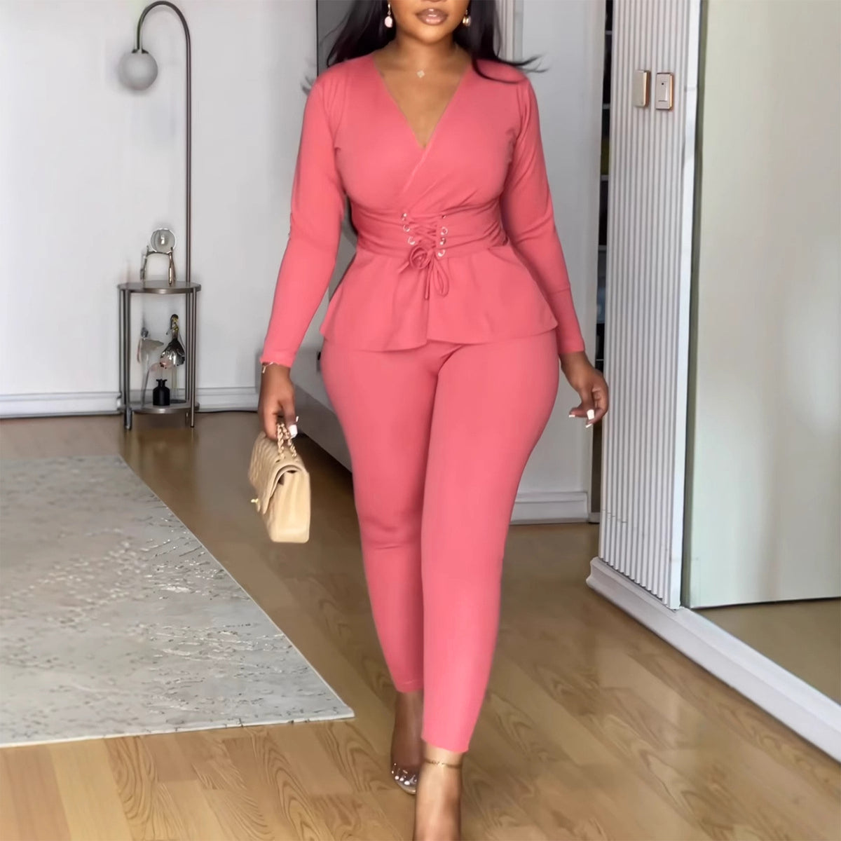 Woman in a pink outfit walking in a room with wooden flooring.