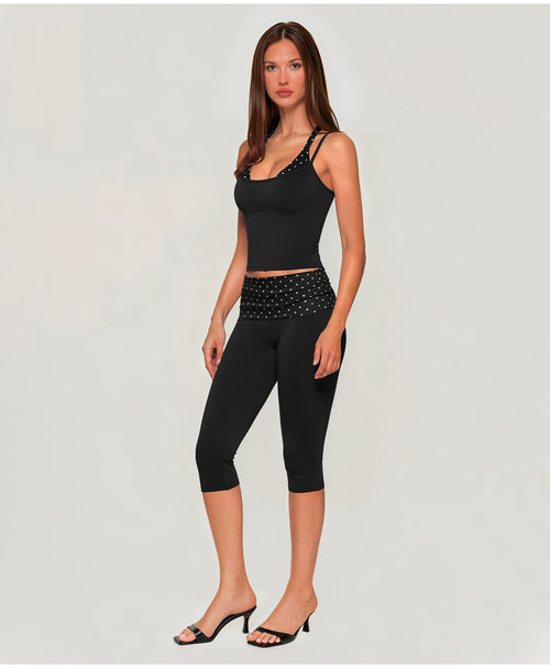 A woman modeling a matching two-piece activewear set in dark olive brown, featuring a scoop-neck tank top with rhinestone-embellished straps and waistband, paired with high-waisted capri leggings with a matching rhinestone waistband, styled with black heeled sandals against a light gray studio background.