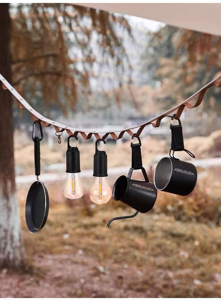 Solar-powered camping lantern with tungsten bulb hanging in a tent outdoors

