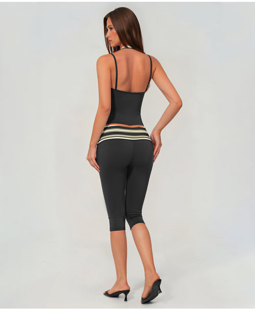 A woman shown from the back wearing a black two-piece activewear set consisting of a spaghetti-strap tank top and matching capri leggings with a horizontal striped waistband.