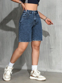 Person wearing high-waisted blue denim shorts with a plain background