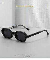 Black geometric square sunglasses with dark lenses and silver-toned metal temples, displayed on a light gray surface with a white window-blind background. Text overlays read 'TEXTURE MATERIAL' and 'XY GLASSES'.