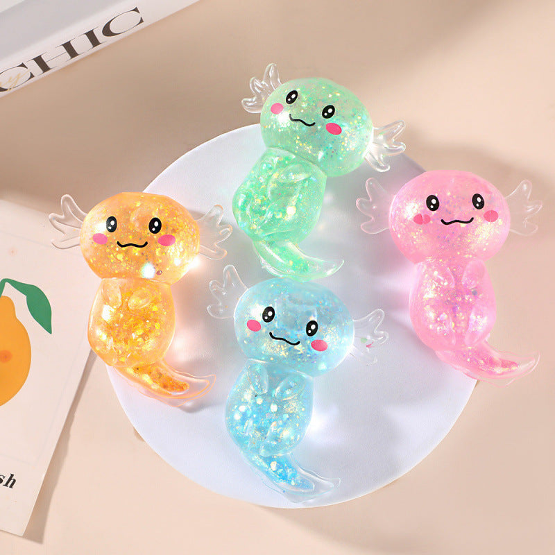 Four colorful, cartoonish axolotl toys on a white plate with a magazine in the background.