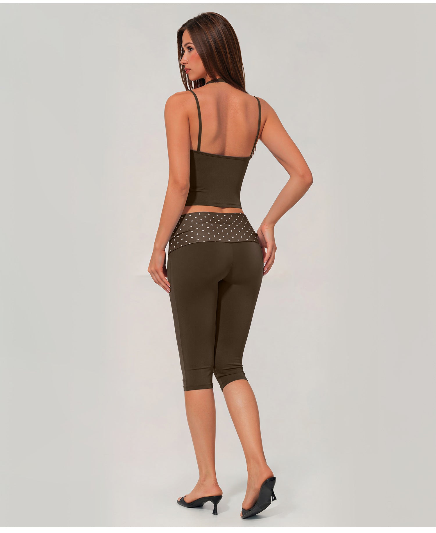 A woman shown from the back wearing an olive green activewear set consisting of a spaghetti-strap crop top and matching high-waisted capri leggings with a sheer mesh waistband.