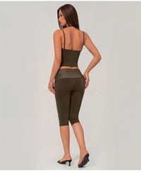 A woman shown from the back wearing an olive green activewear set consisting of a spaghetti-strap crop top and matching high-waisted capri leggings with a sheer mesh waistband.