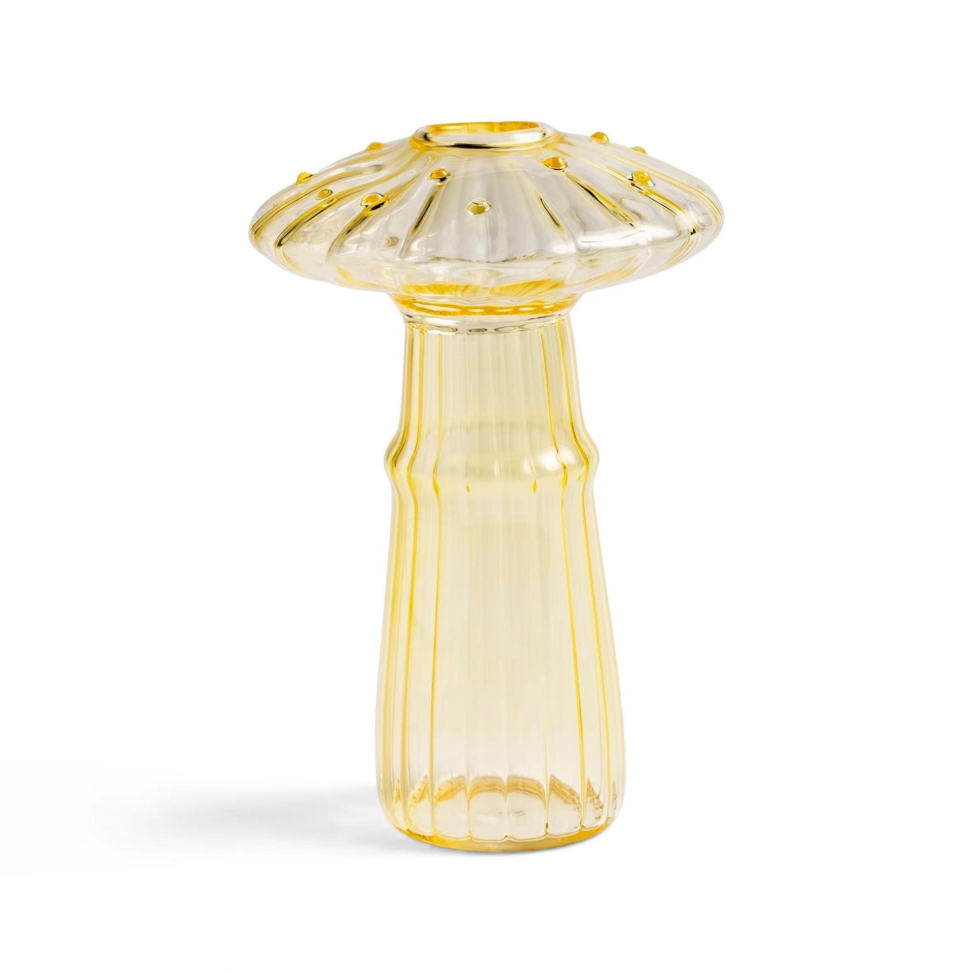 Clear glass mushroom-shaped vase with hydroponic plant and flowers on a minimalist home table


