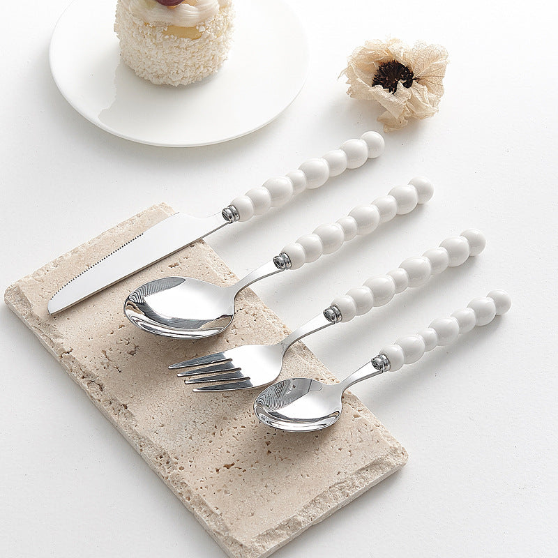 Set of 4 high-end stainless steel cutlery with colorful pearl handles on an elegant dining table