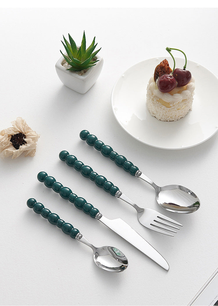 Set of 4 high-end stainless steel cutlery with colorful pearl handles on an elegant dining table