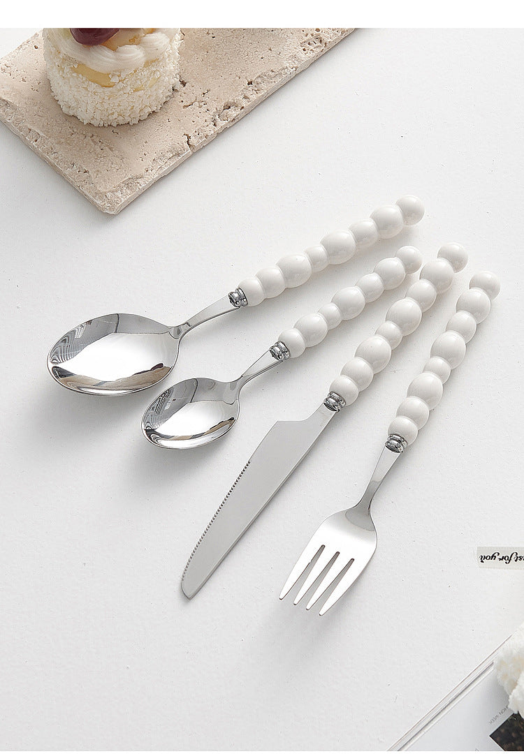 Set of 4 high-end stainless steel cutlery with colorful pearl handles on an elegant dining table
