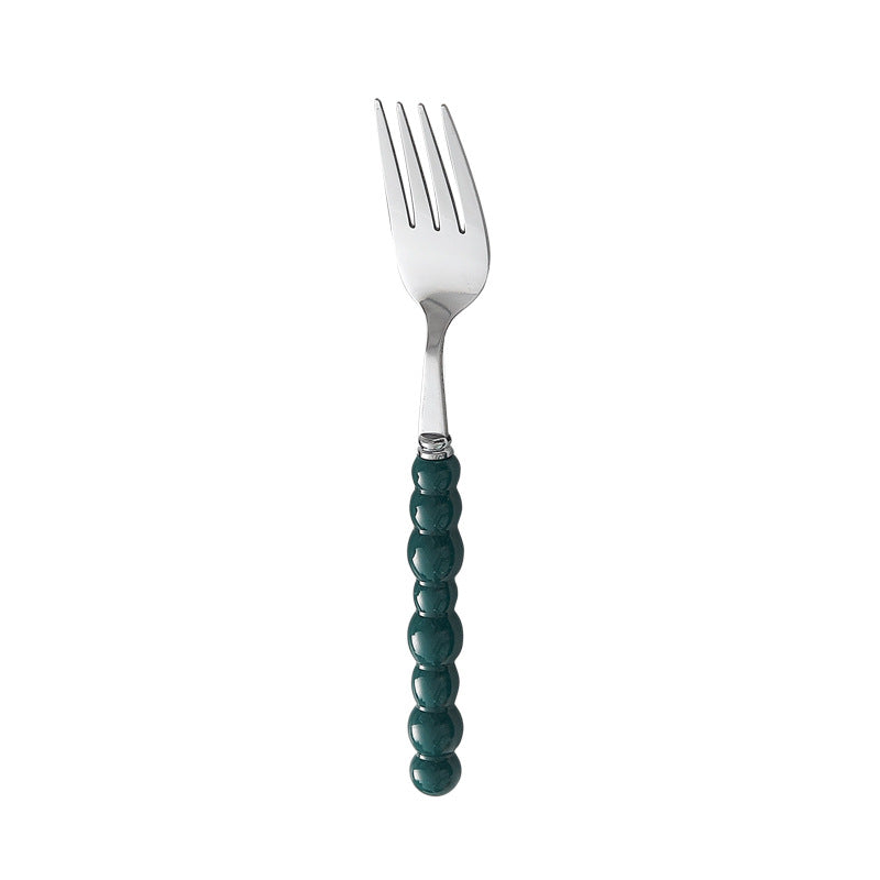 Set of 4 high-end stainless steel cutlery with colorful pearl handles on an elegant dining table