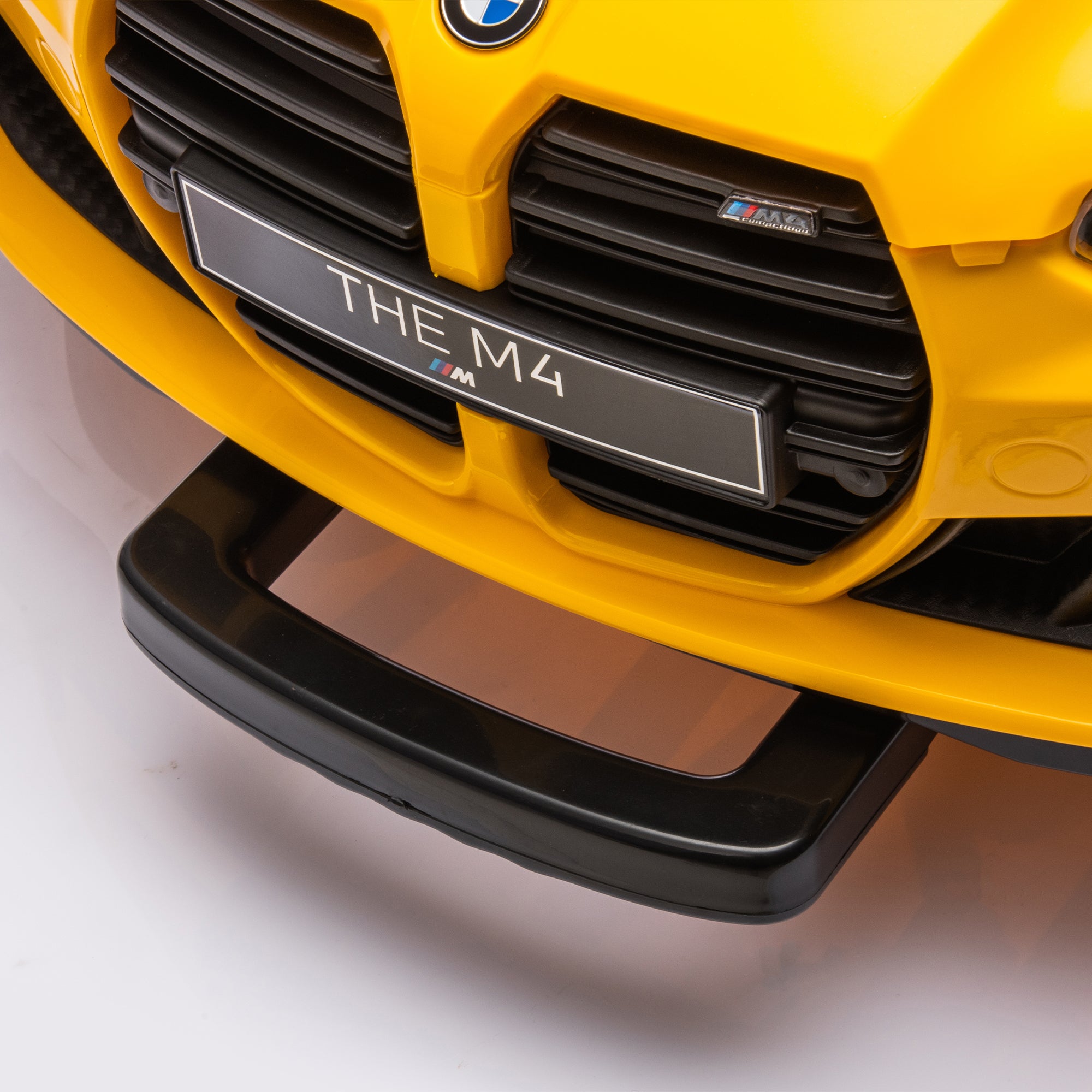 Yellow BMW M4 12V electric ride-on car for kids, featuring authentic design with working headlights, MP3 player, and forward/reverse motion. Comes with adjustable seat and steering wheel, providing a realistic driving experience for children aged 3-6